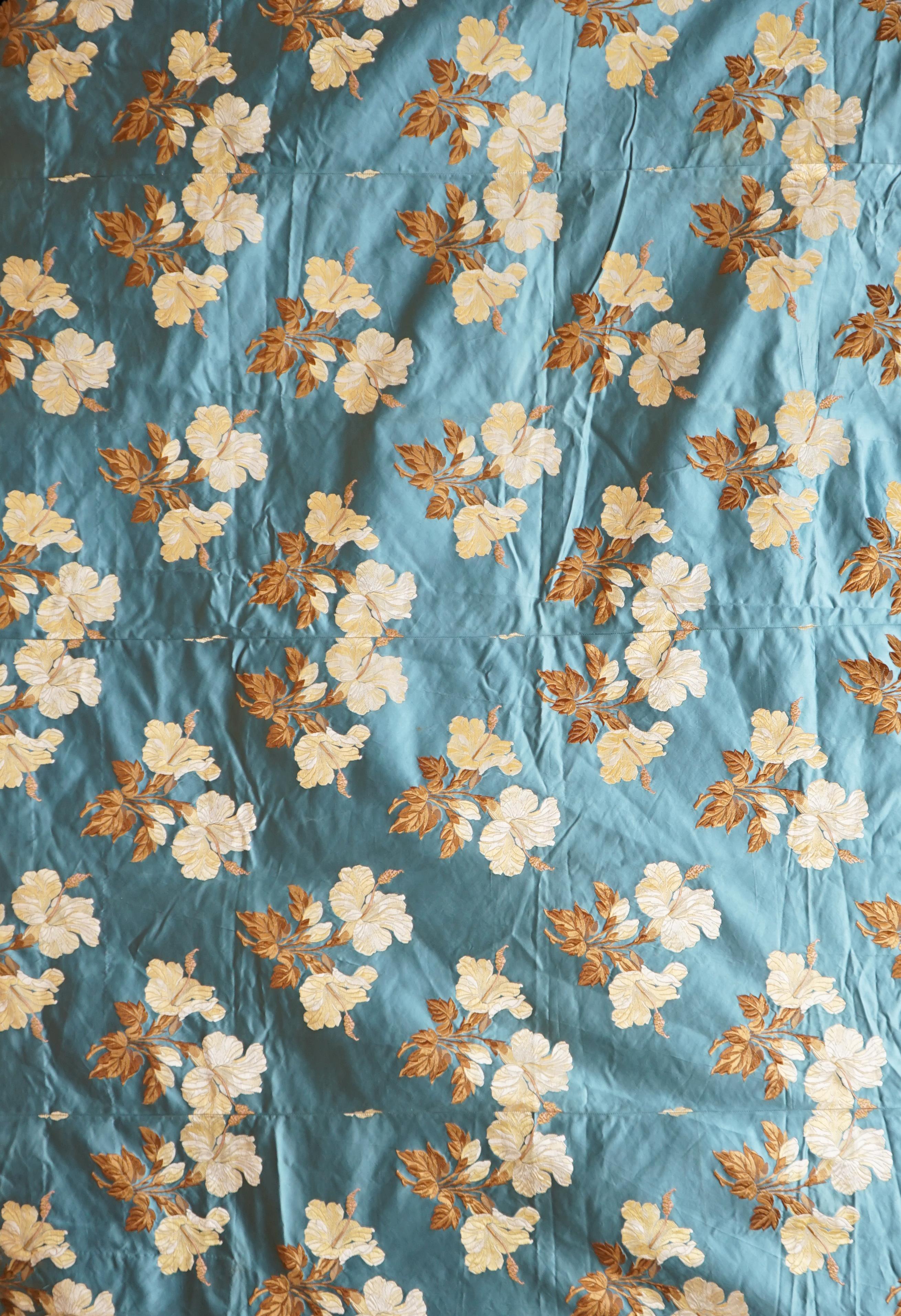 A turquoise satin floral silk brocaded panel of four 59cm widths, boldly embroidered in yellow and brown strays of lilies, the panel possibly part of a pelmet or half tester bed, each spray being 21cm high as a diagonal